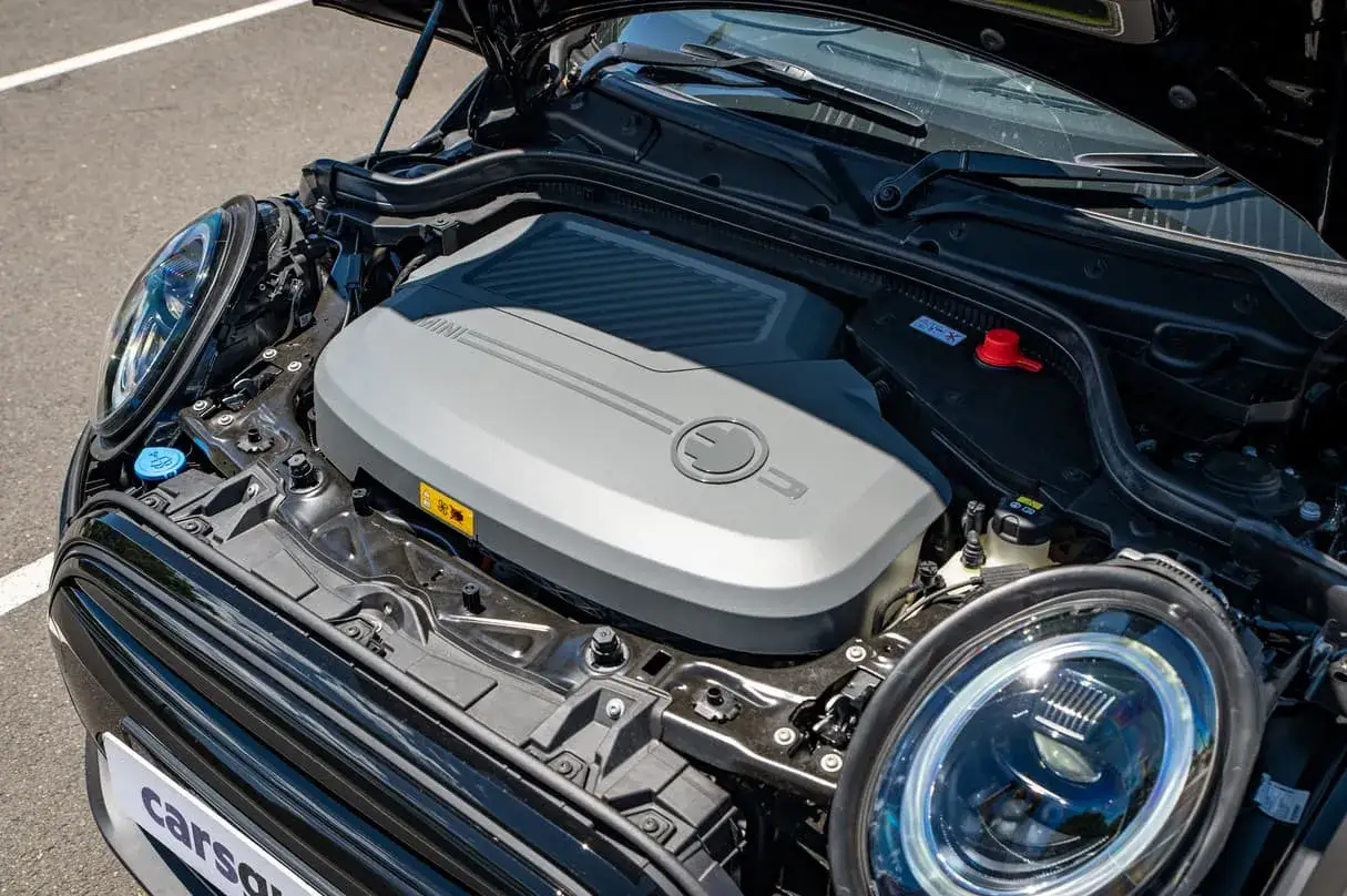 Otwarta maska czarnego Mini Cooper ukazuje nowoczesne **mini cooper silniki** elektryczne.
