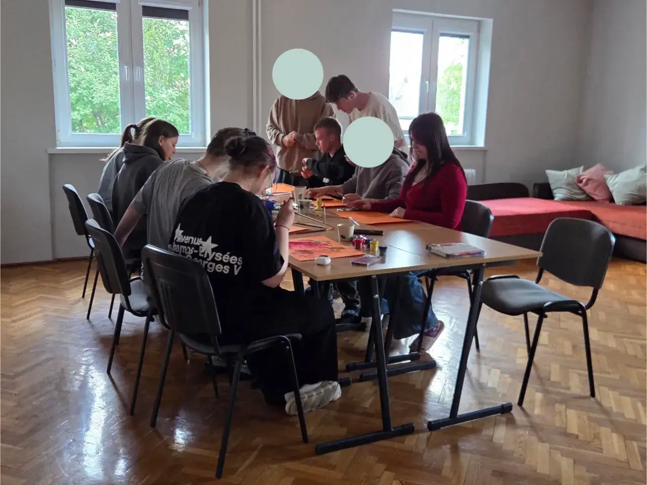 Młodzież z **szkoły z internatem** tworzy artystyczne dzieła przy stole, malując i rysując.