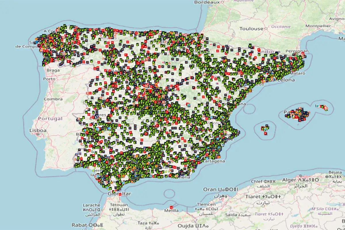 Mapa de España y Portugal con miles de puntos verdes, rojos y negros indicando la ubicación de cargadores públicos para coches eléctricos.