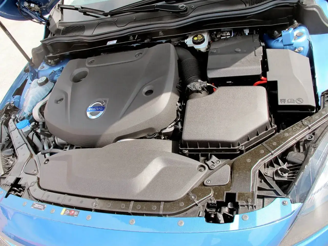 Motorutrymme p&aring; en bl&aring; Volvo V60. T&auml;nker du p&aring; kamremsbyte Volvo V60 pris?