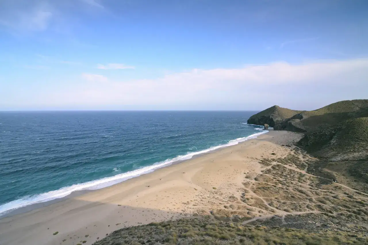 Weite Sandstr&auml;nde und das t&uuml;rkisfarbene Meer am Playa de los Muertos. Sanfte H&uuml;gel s&auml;umen die K&uuml;ste unter einem klaren Himmel.
