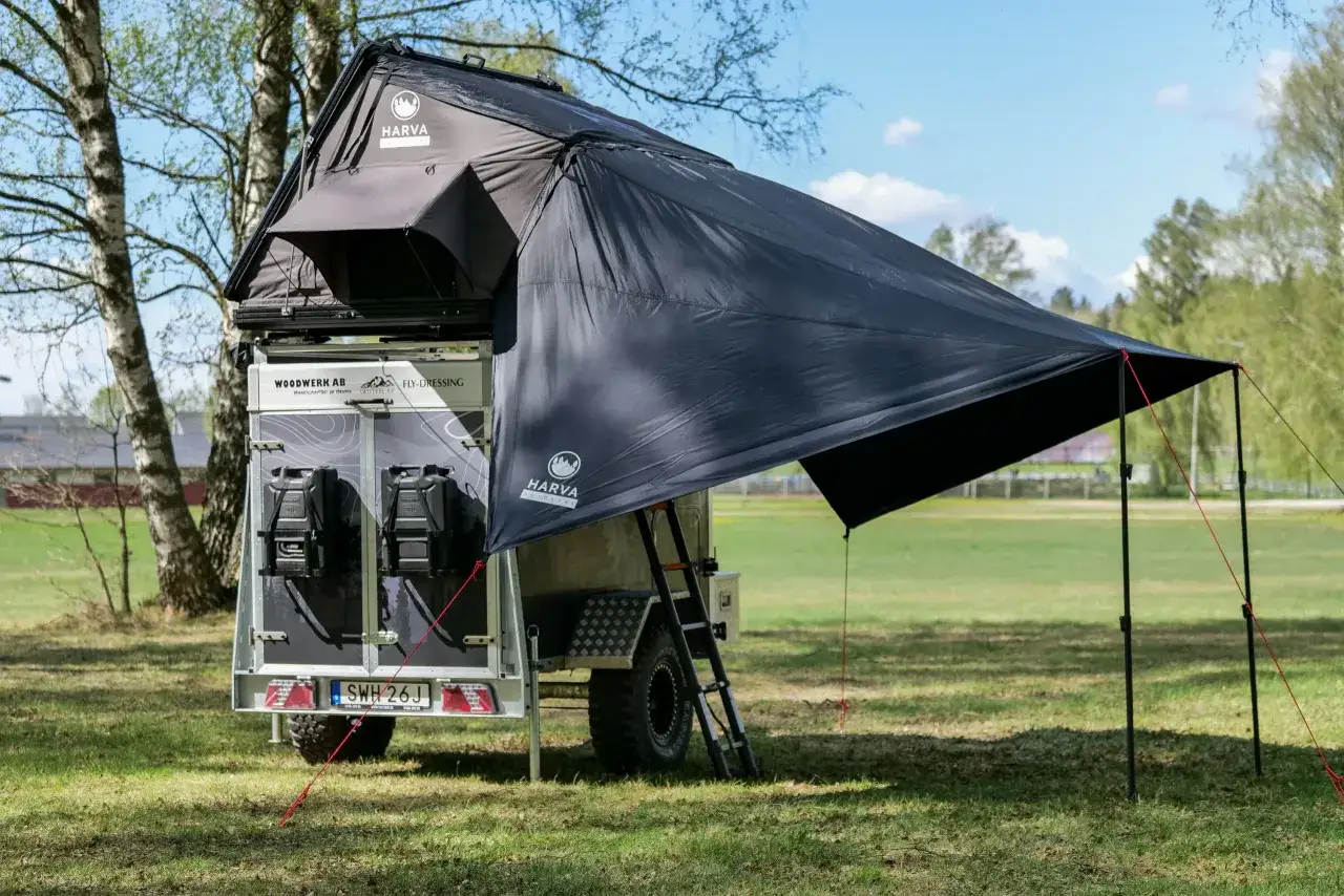 Ett tak med ett svart vindskydd presenning f&auml;st vid en takbox p&aring; en sl&auml;pvagn. Perfekt f&ouml;r camping&auml;ventyr.