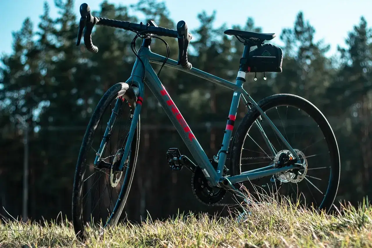 Szary rower crossowy z czerwonymi akcentami, gotowy na przygodę. Idealny na leśne ścieżki, choć równie dobrze sprawdzi się jako rower mtb.