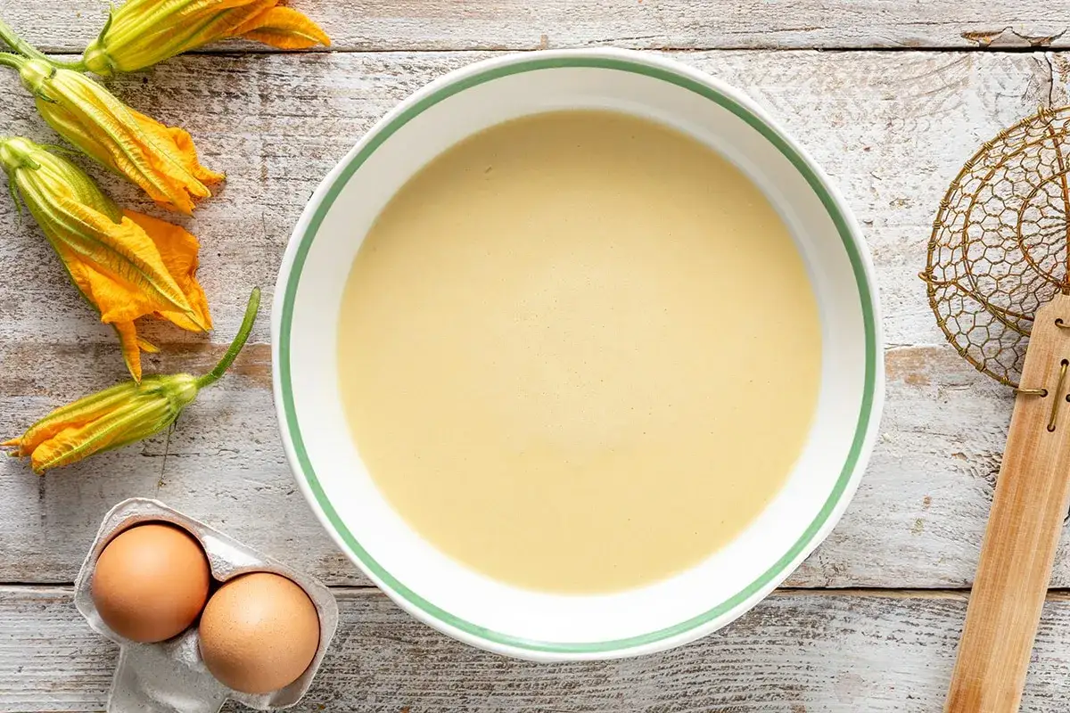Fiori di zucca freschi pronti per essere immersi nella pastella dorata. Ingredienti per un piatto gustoso.