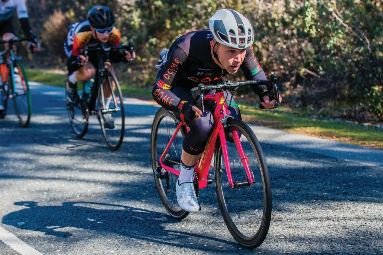 Cyclist with a VO2 max of 50 pushes hard on a bright pink bike, racing uphill with determination.