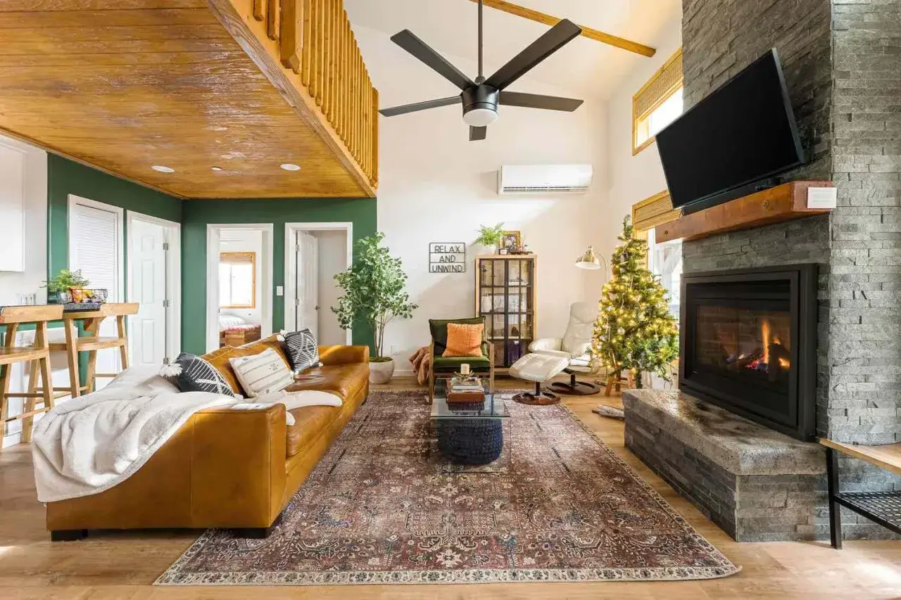 Cozy cottagecore house living room with a leather sofa, fireplace, Christmas tree, and rustic wooden accents.