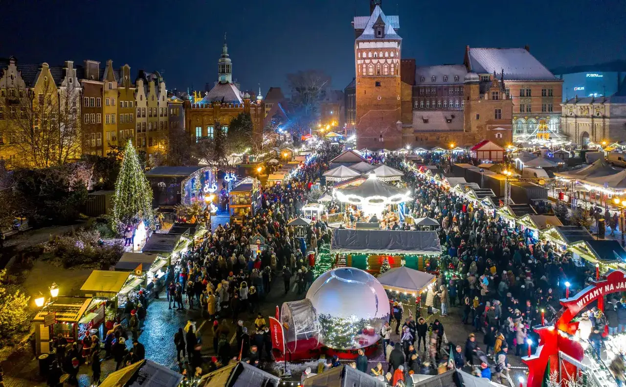 Tłum ludzi na jarmarku w Gdańsku 2025, wśród straganów, karuzeli i choinki.