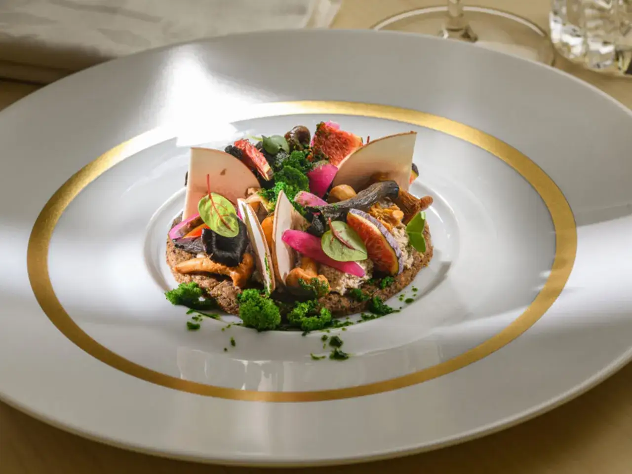 Une assiette élégante présente une **Metz spécialité culinaire** : un tartare de légumes et fruits, garni de figues, champignons et herbes fraîches.