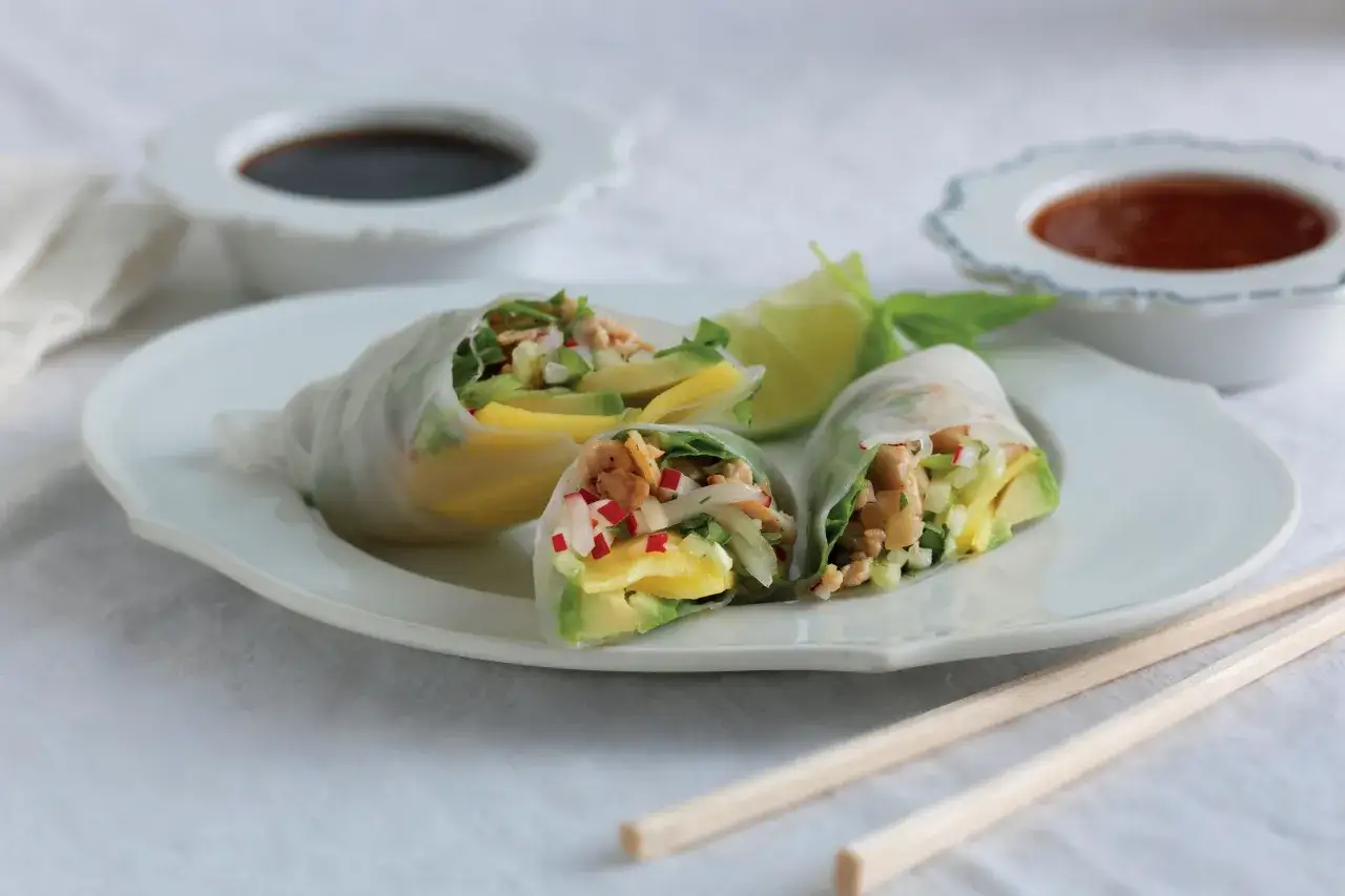 Färska vietnamesiska vårrullar med mango, avokado och grönsaker, serverade med dippsåser och ätpinnar.
