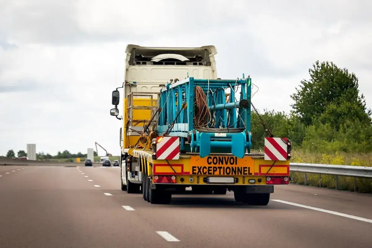 Camion transportant une charge hors norme sur l'autoroute. Il s'agit d'un convoi exceptionnel cat&eacute;gorie 1, avec une structure bleue sur la remorque.