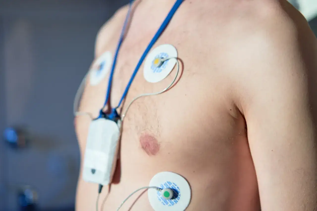 Mężczyzna z elektrodami EKG na klatce piersiowej, monitoruje swój wysoki puls.