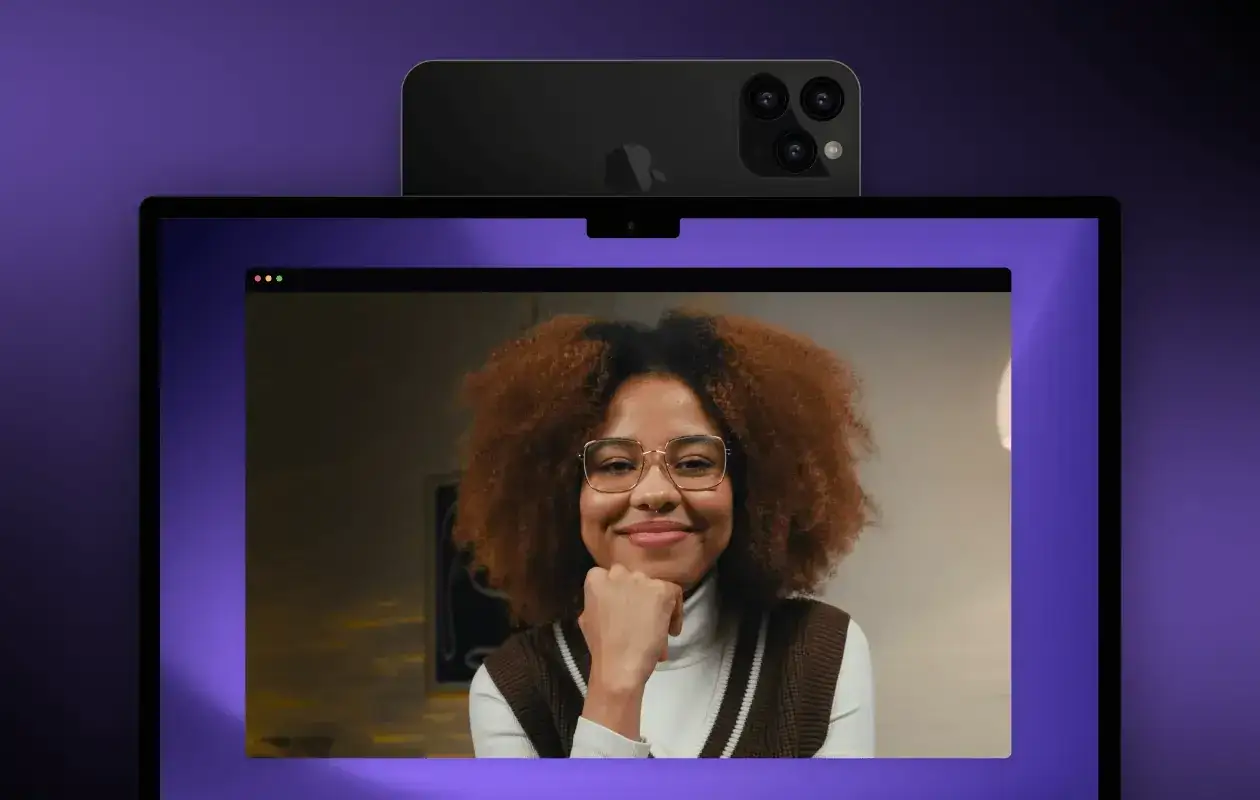 Ein **iPhone als Webcam** verbessert die Videoqualität. Eine Frau mit lockigem Haar und Brille lächelt in die Kamera.