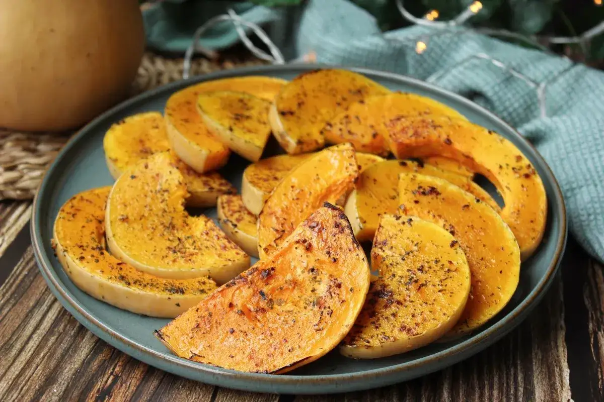 Rodajas de calabaza a la plancha, doradas y sazonadas, servidas en un plato azul. Un plato sencillo y delicioso.