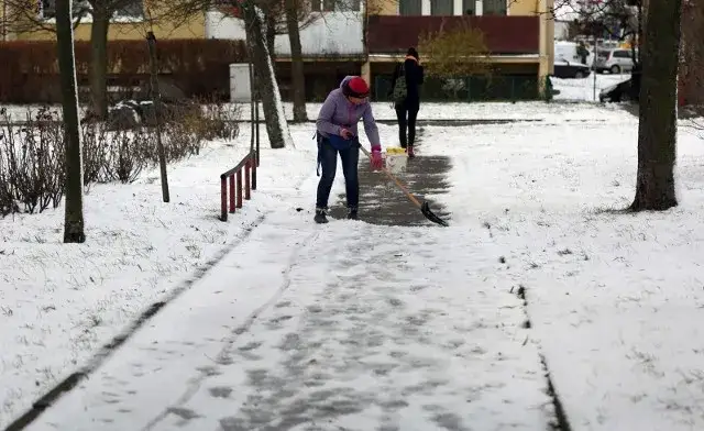 osoba odśnieżająca mały chodnik i duży podjazd