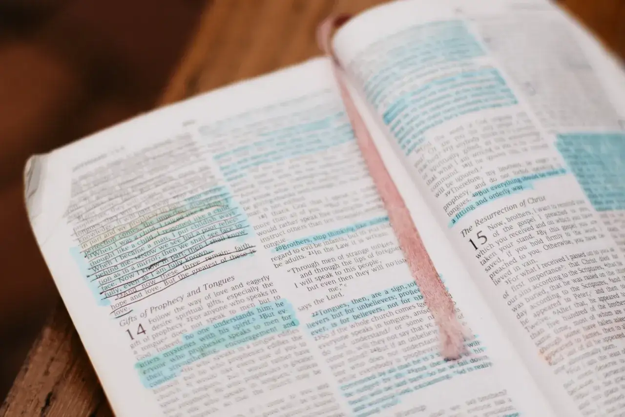 Open Bible with highlighted verses. A pink ribbon marks a page discussing spiritual gifts and whether you can lose your salvation.