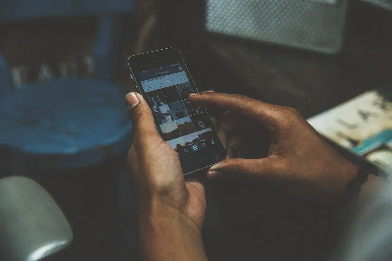 Dłonie trzymają smartfon z widocznym profilem Instagrama. Czy na odwyku można mieć telefon? To pytanie nurtuje wielu.