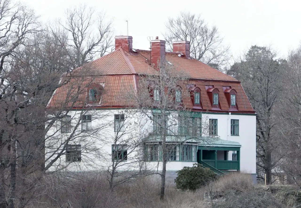 Vitt hus med tegeltak och gröna detaljer, omgivet av träd. Kanske här var bor prinsessan Madeleine?