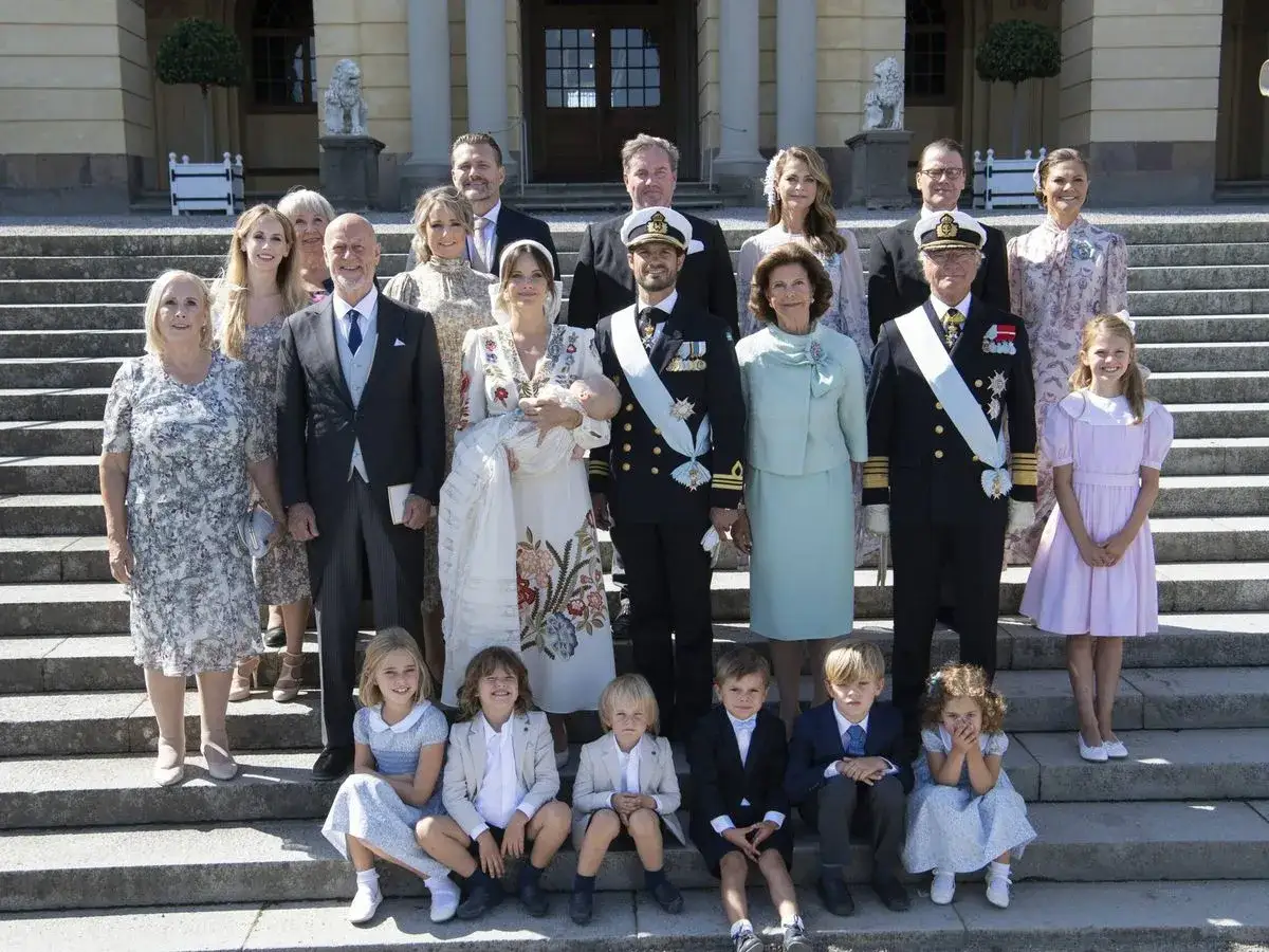 Familia real posa con el bebé en su bautizo. El **outfit bautizo** del bebé es un traje blanco con bordados.