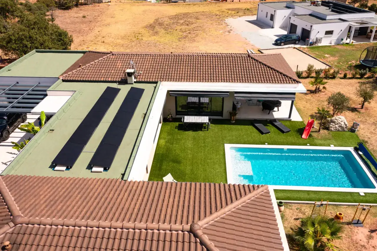 Vue aérienne d'une maison moderne avec piscine et **tva panneaux photovoltaïques** sur le toit plat.
