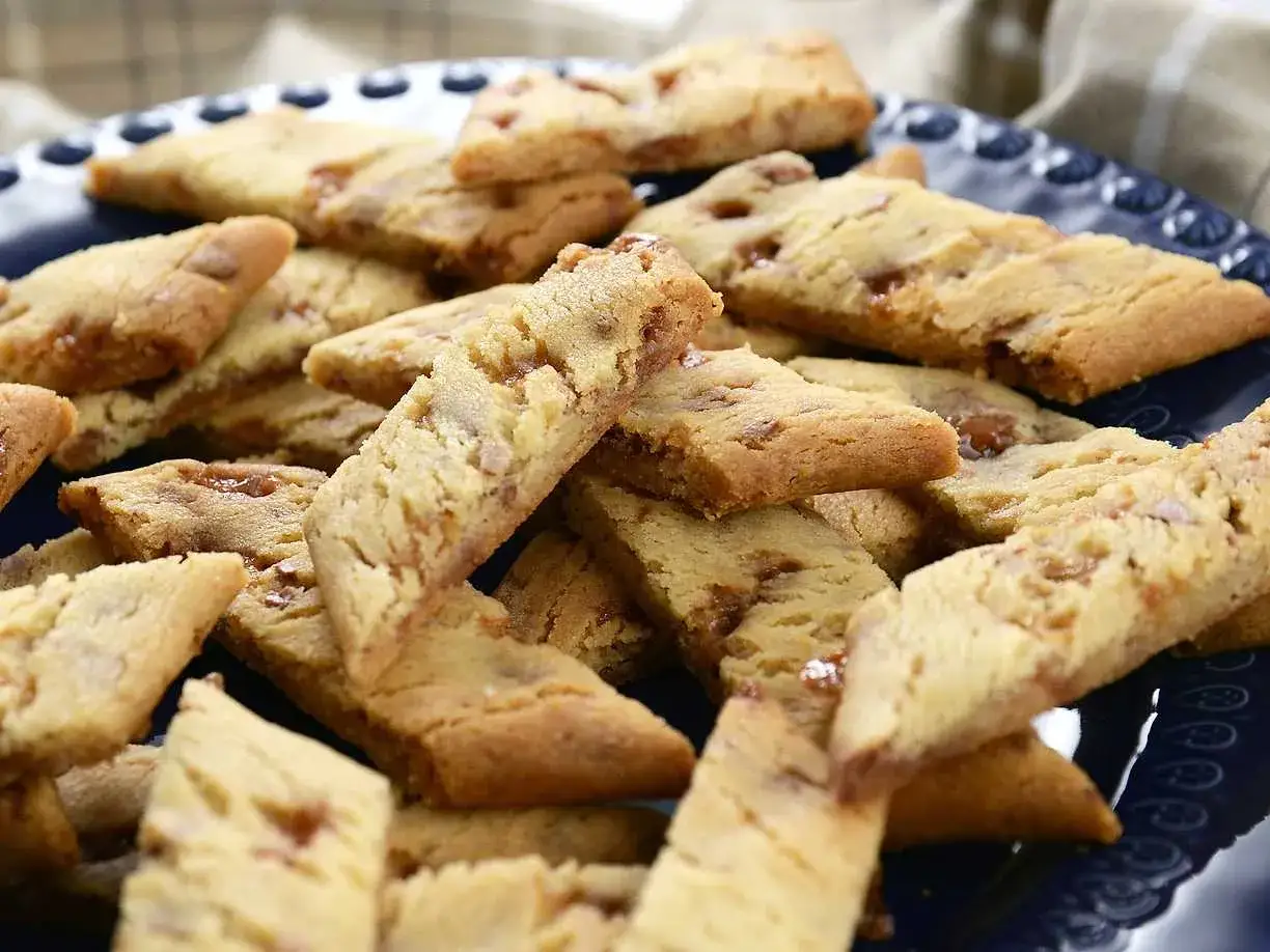 En hög med gyllene kolasnittar med bitar av knäckig Daim. Perfekt till fikat!