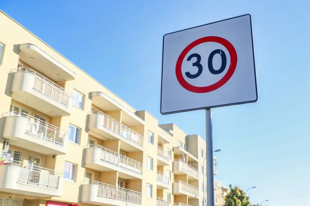 Znak ograniczenia prędkości do 30 km/h przed blokiem mieszkalnym. Uważaj na predkosci na drodze w tej okolicy.