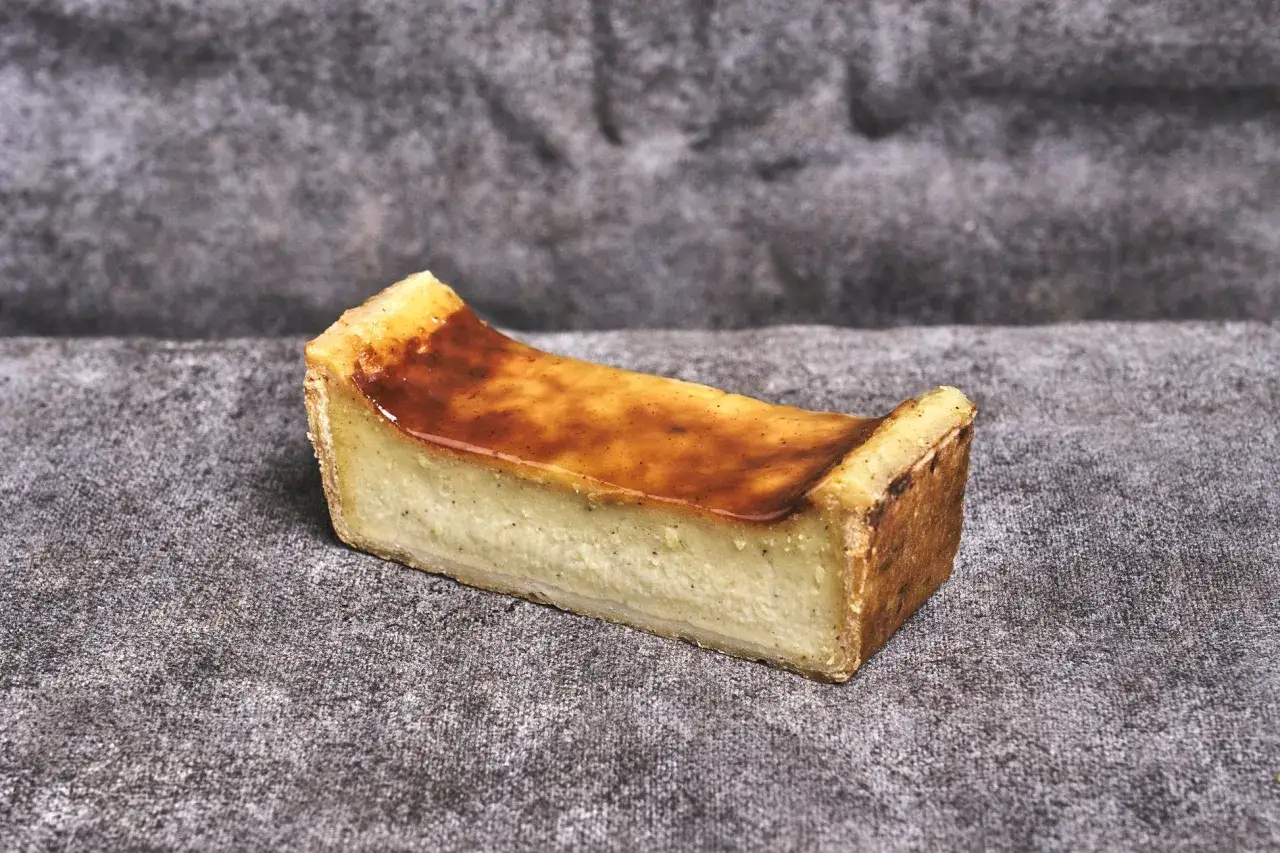 Une part de flan aux œufs, crémeux et doré, sur un fond texturé.