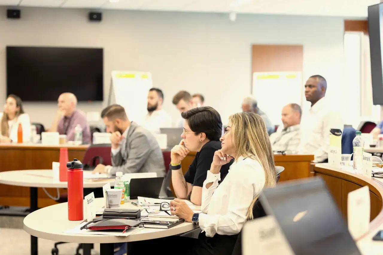 Attendees at a seminar, focused and engaged, leaning forward to absorb new information at the **growth edge** of their learning journey.