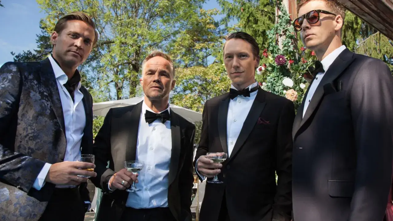 Fyra m&auml;n i kostym, med drinkar i handen, ser ut som karakt&auml;rer fr&aring;n en norsk serie.
