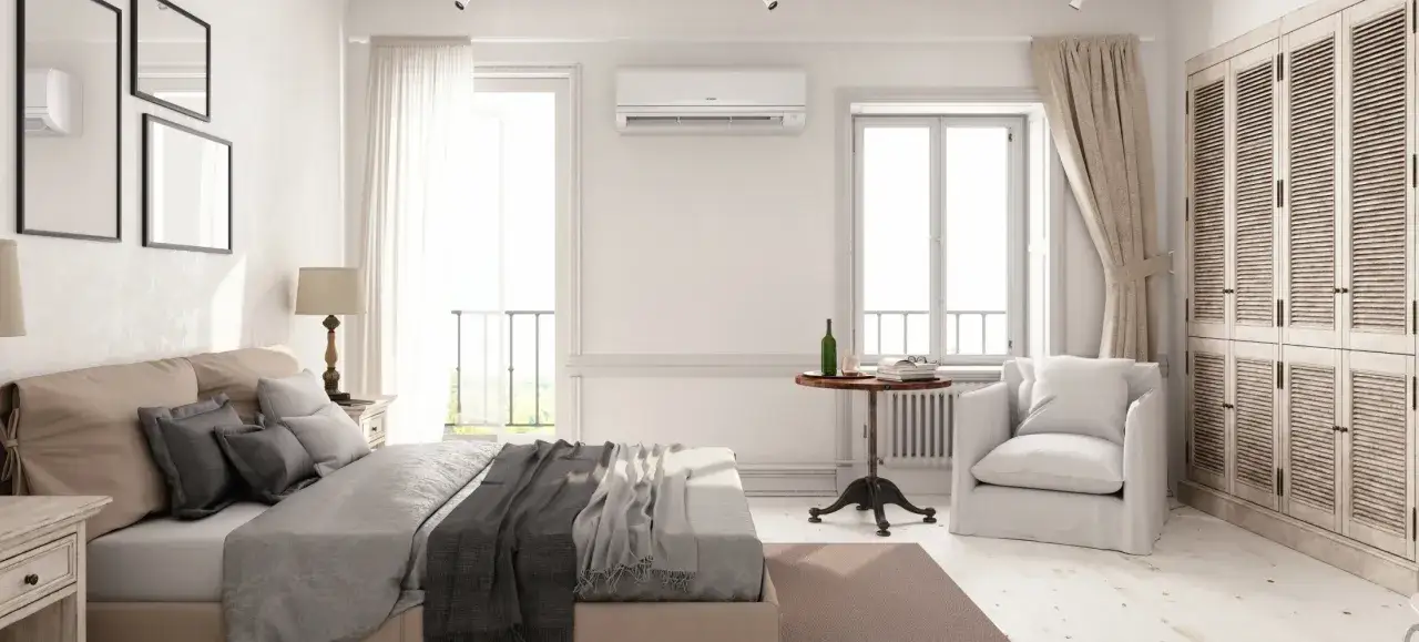Un dormitorio luminoso con cama, armario y aire acondicionado. La unidad de aire acondicionado está colocada estratégicamente en la pared, mostrando dónde colocar el aire acondicionado en un dormitorio para una climatización óptima.