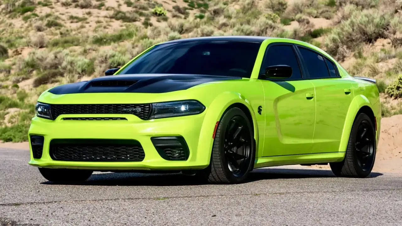 Jaskrawozielony Dodge Charger SRT z czarną maską i dachem, zaparkowany na drodze w pustynnym krajobrazie.