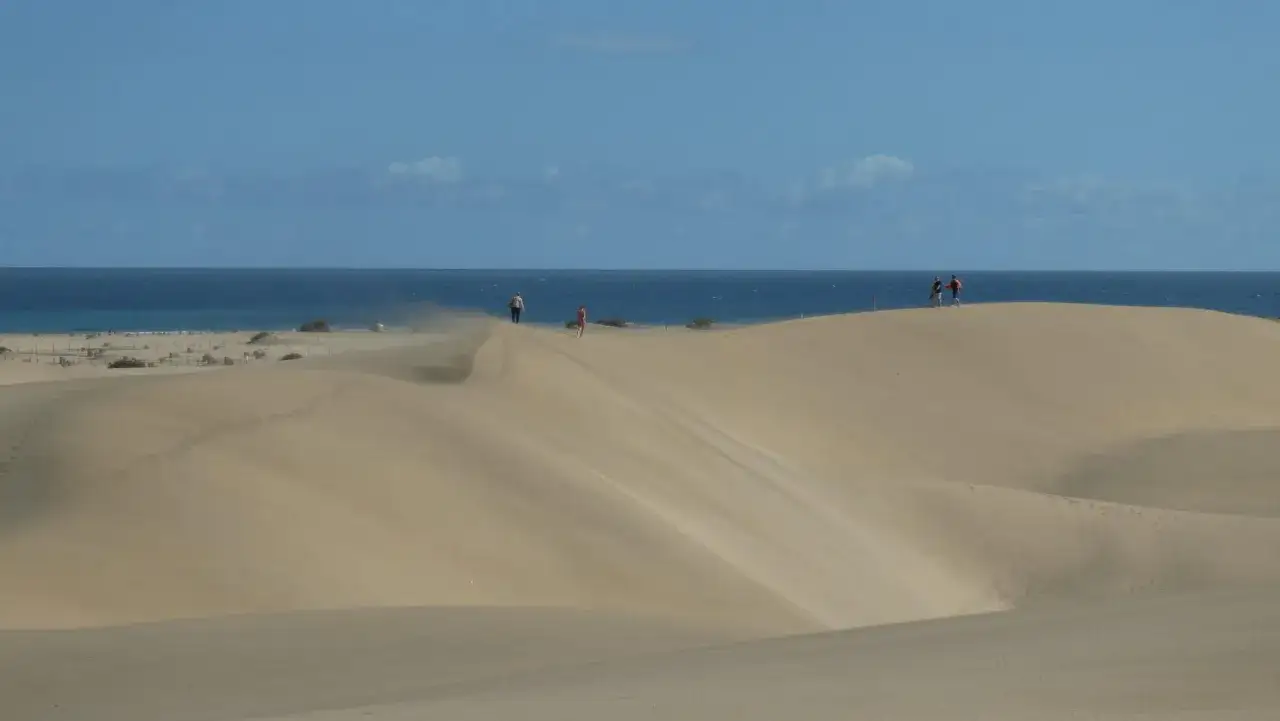 Plaża na Wyspach Kanaryjskich z turystami, symbolizująca europejski standard wypoczynku