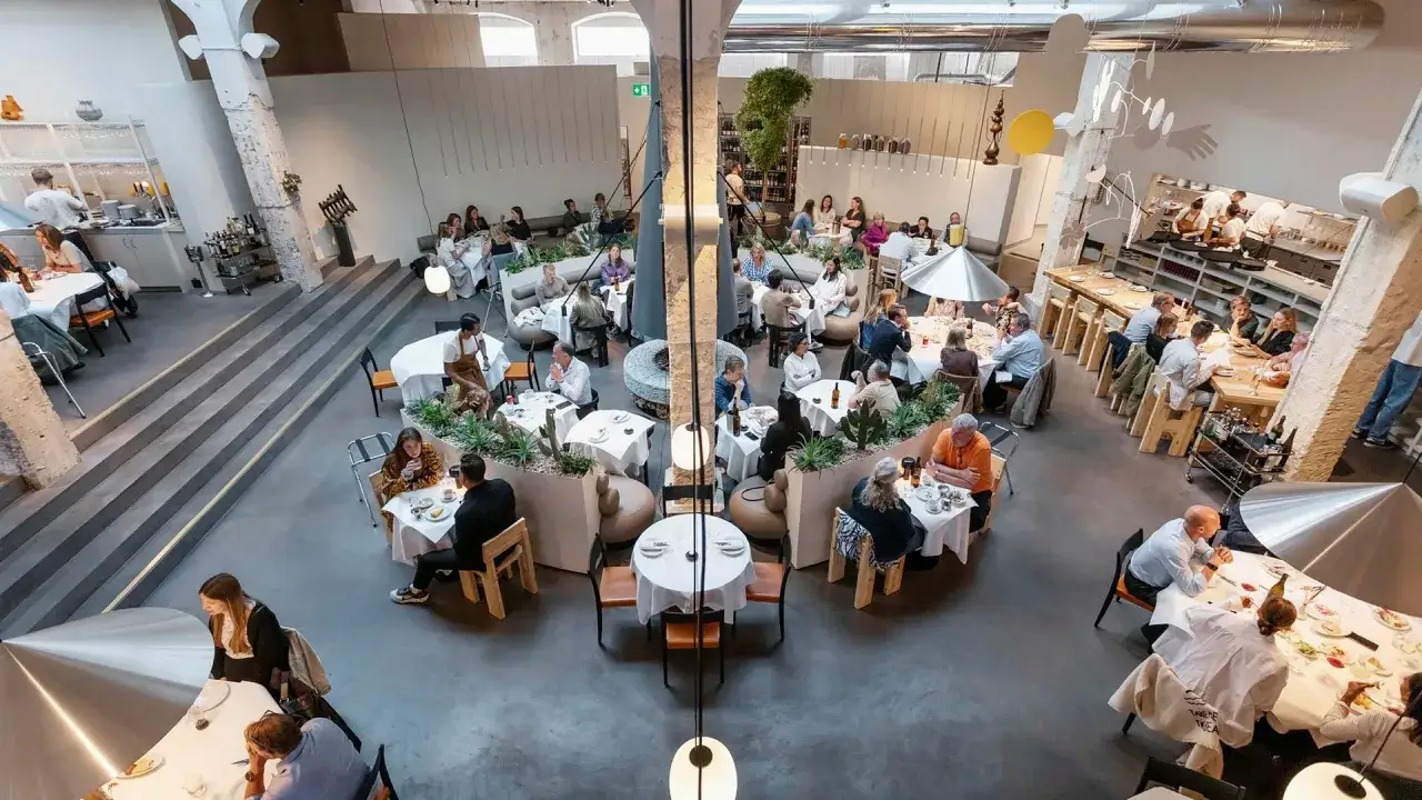 En livlig restaurang i slakthusområdet Stockholm, med gäster som njuter av mat och sällskap vid dukade bord.