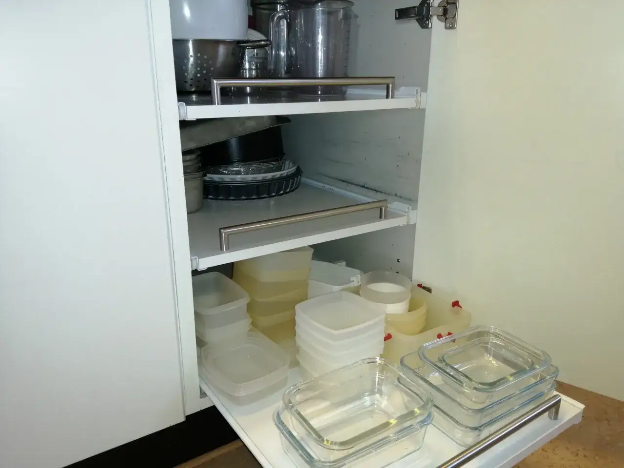 K&ouml;ksf&ouml;rvaring med utdragbara hyllor. En hylla visar k&ouml;ksredskap, en annan staplade plast- och glasburkar.