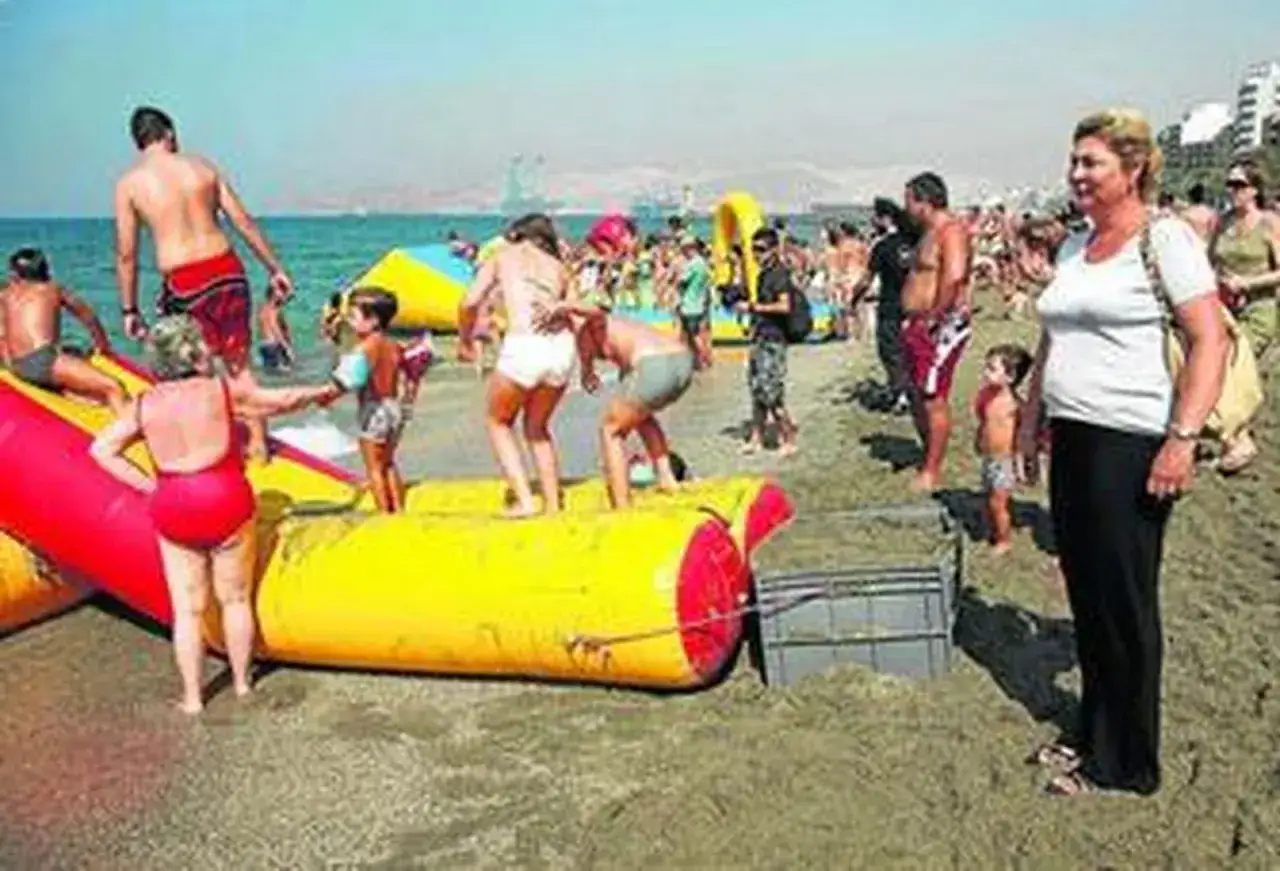 Gente disfrutando de los juegos inflables en la playa del Zapillo. Niños y adultos se divierten bajo el sol en un día soleado.