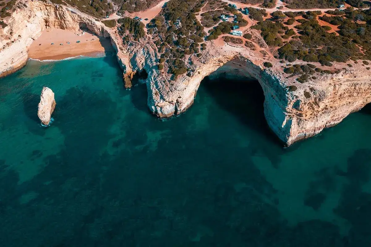 Versteckter Strand an der Algarve: Eine einsame Felsnadel ragt aus dem t&uuml;rkisfarbenen Meer vor einer H&ouml;hle. Ein echter Geheimtipp!