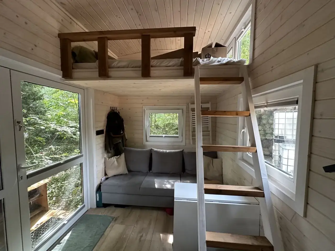 Clevere tiny house bett ideen: Schlafempore &uuml;ber gem&uuml;tlicher Couch, mit Leiter und Fensterblick ins Gr&uuml;ne.
