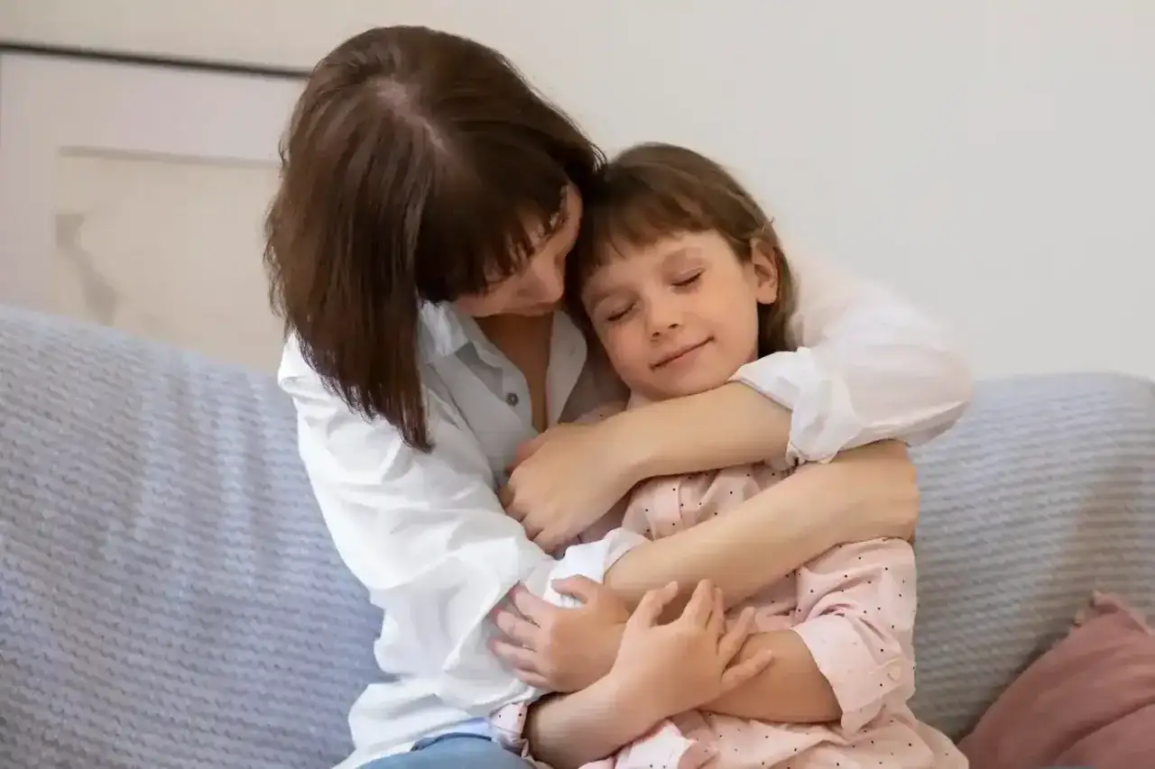 Madre abraza a su hija con ternura, un momento de conexi&oacute;n profunda que evoca la seguridad y el amor de la regresi&oacute;n infantil.