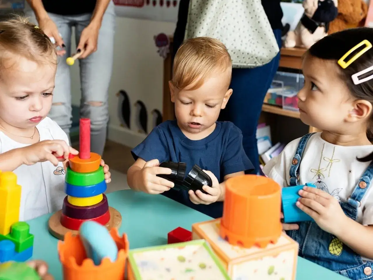 Niños jugando con bloques y torres de colores en una guardería gratis. Aprenden y se divierten mientras sus padres trabajan.