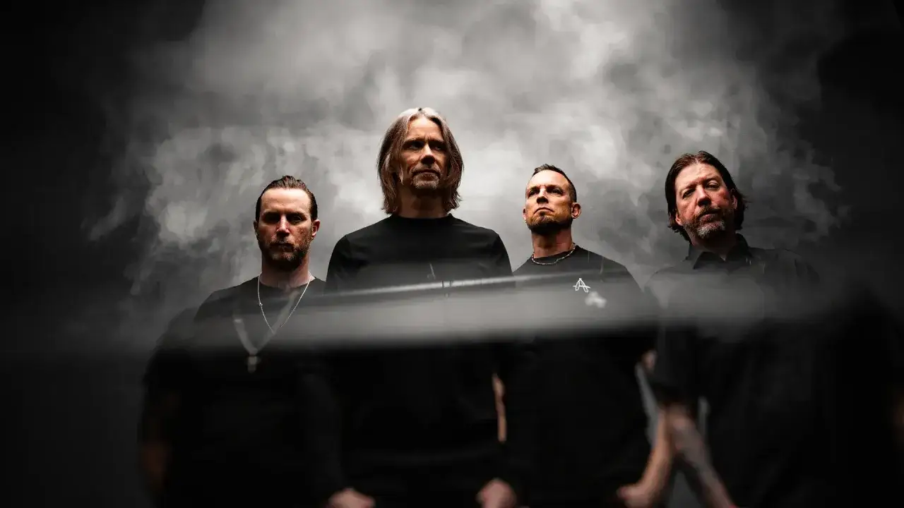 Alter Bridge Sverige: bandmedlemmar i m&ouml;rka kl&auml;der, med r&ouml;kig bakgrund.