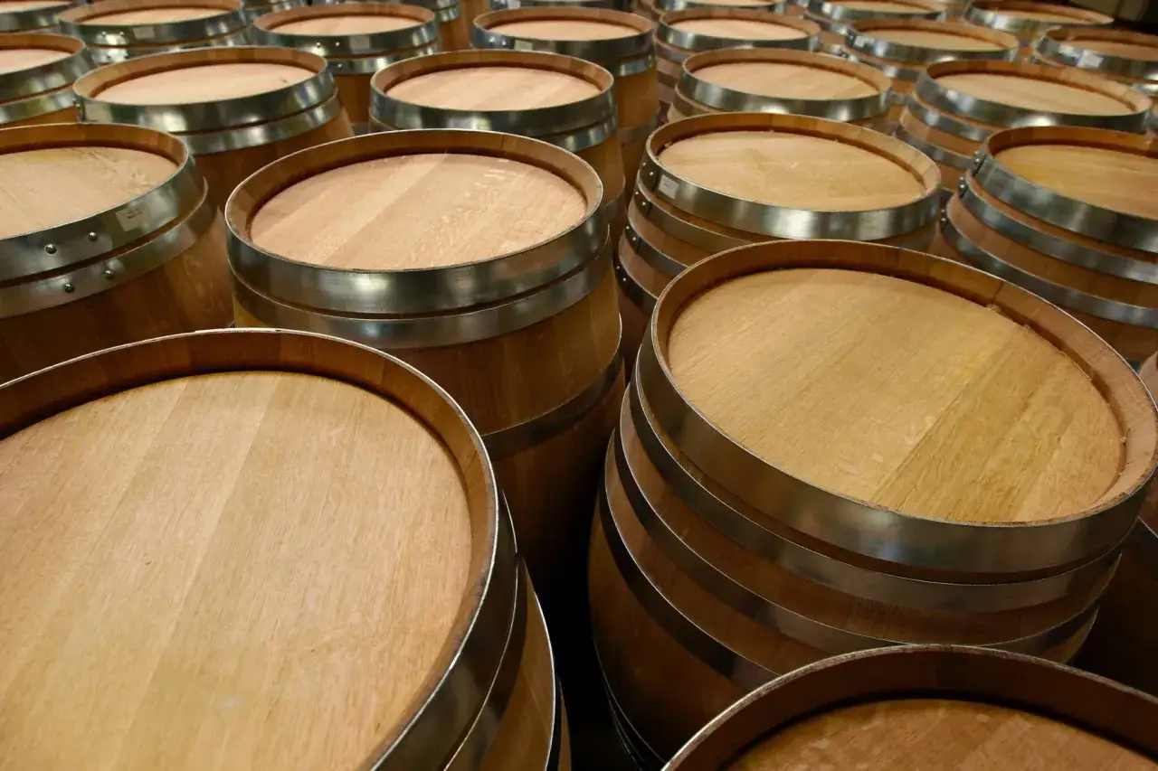 Fila di botti di legno, pronte per la stagionatura. La loro capacità barrique è fondamentale per affinare vini e distillati.