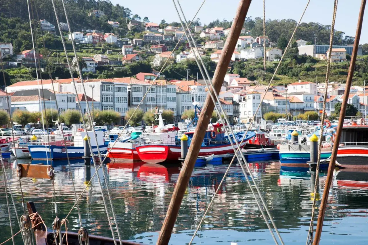 Puerto pesquero con barcos de colores y casas en la ladera. Un lugar encantador que ver cerca de Santiago de Compostela.