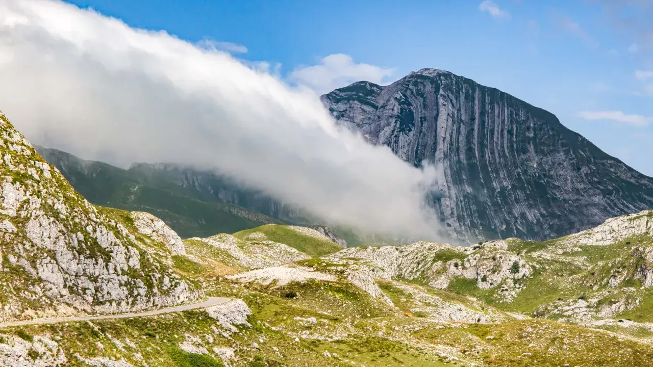 Dramatic clouds sweep across a rugged mountain landscape in Montenegro. This view makes you wonder how many days in Montenegro would be enough to explore all its beauty.