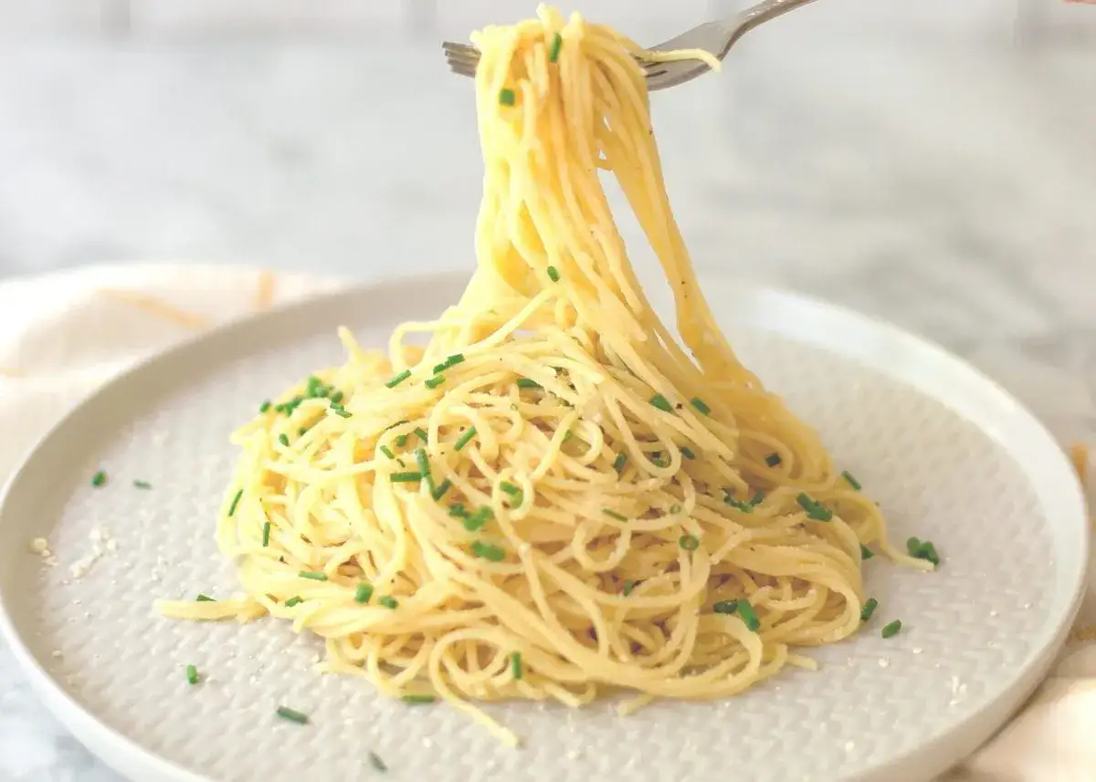 Porcja spaghetti z parmezanem i szczypiorkiem. Niska zawartość parmezanu wpływa na niski indeks glikemiczny dania.