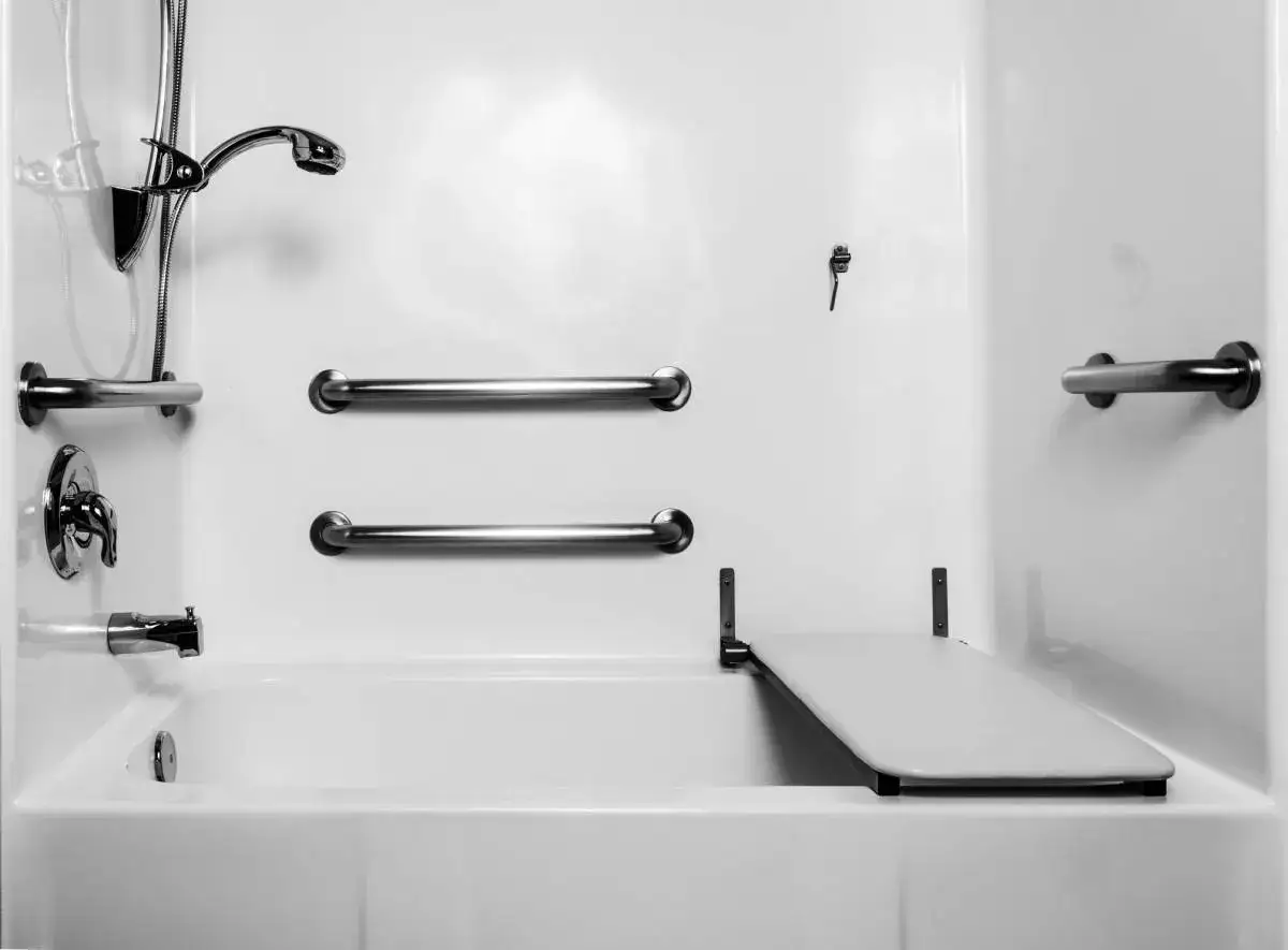 Salle de bain adaptée avec barres d'appui et siège rabattable, idéale pour un prêt à taux zéro pour personne handicapée.