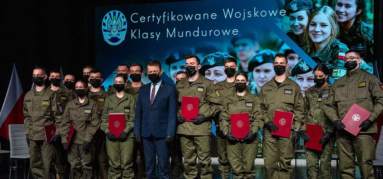 Młodzi żołnierze RP w mundurach odbierają certyfikaty. Uśmiechnięci, z dumą prezentują dokumenty.