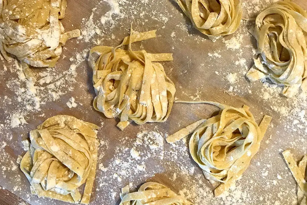 Nids de pâtes fraîches, saupoudrés de farine, prêts pour une recette de pâte italienne gastronomique.