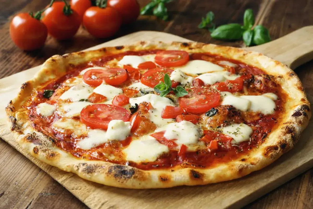 Pizza Margherita avec une garniture g&eacute;n&eacute;reuse de tomates fra&icirc;ches et de mozzarella fondante, sur une planche en bois.