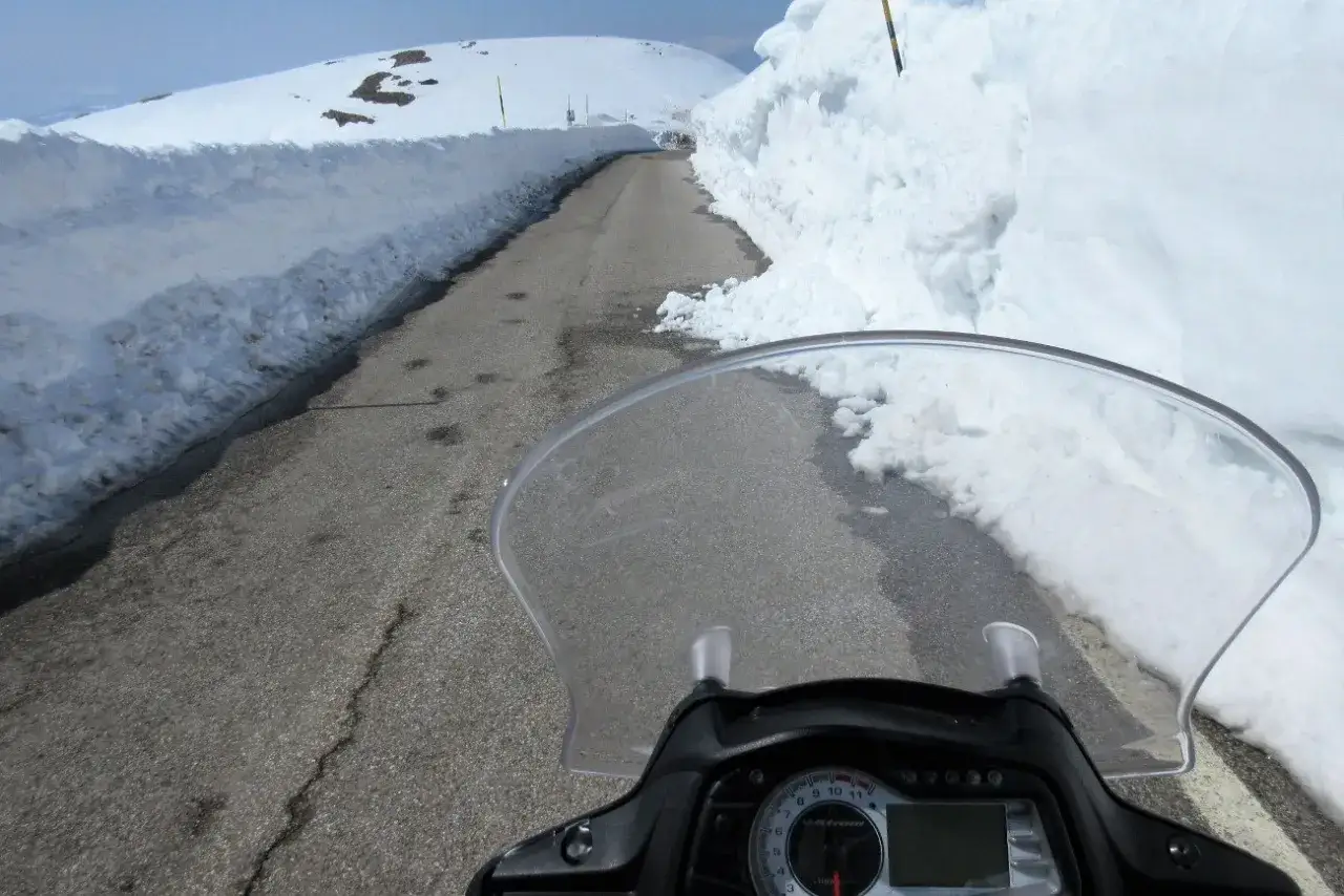 Strada innevata, un'avventura in moto inverno con alte pareti di neve ai lati.