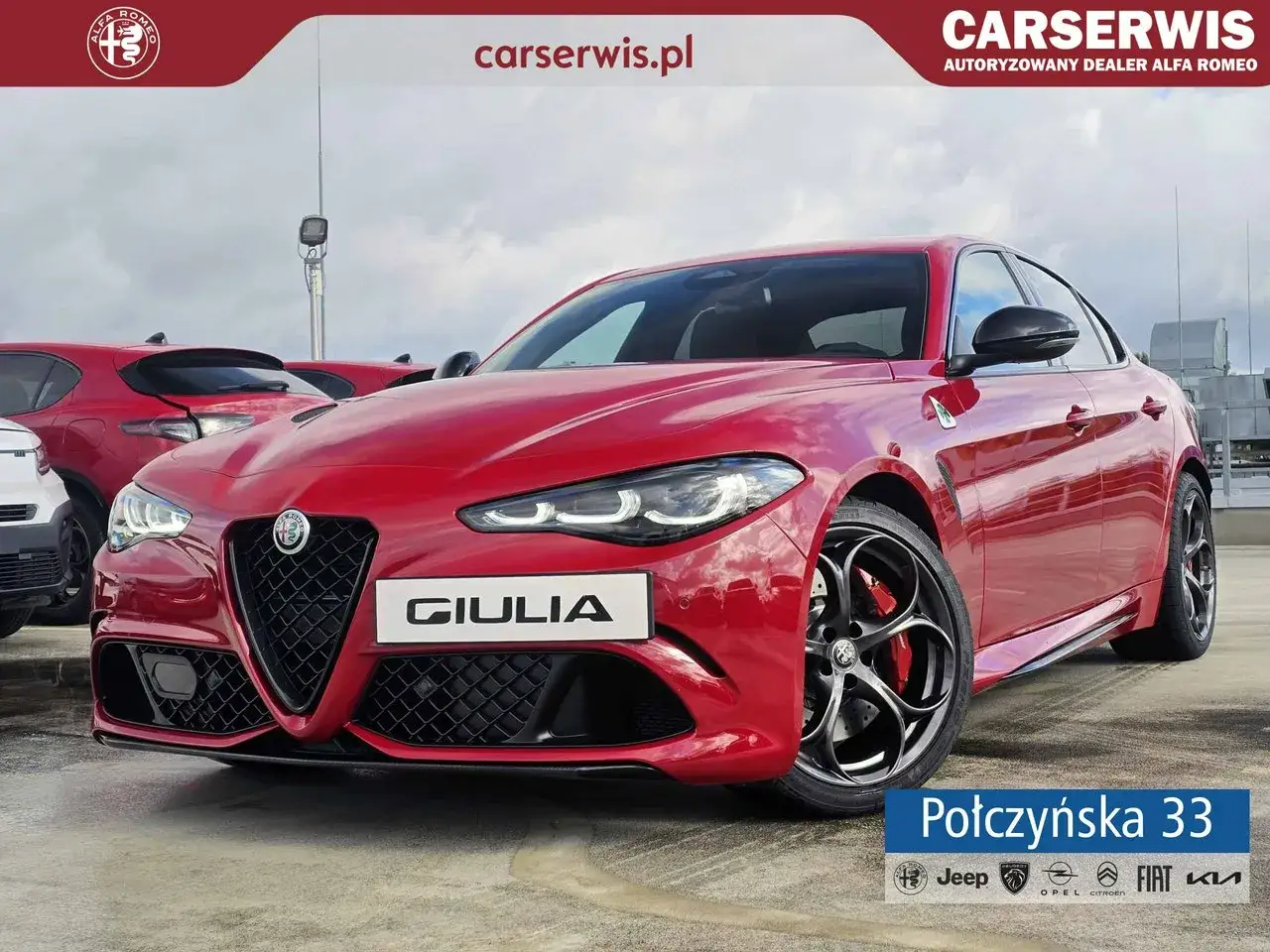 Czerwona Alfa Romeo Giulia Quadrifoglio z czarnymi felgami i detalami, zaparkowana na zewnątrz.