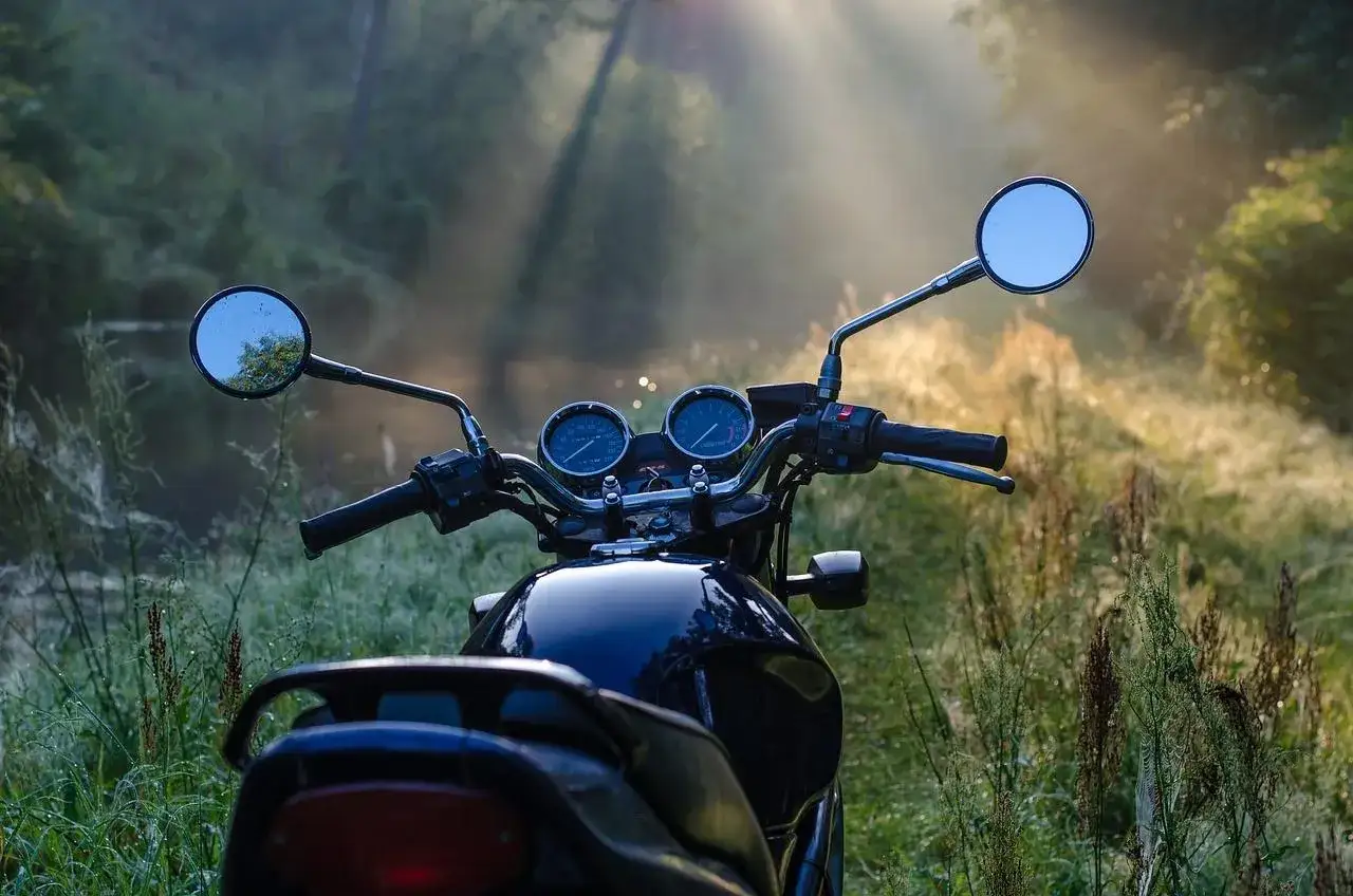 Manubrio di moto scura in un prato nebbioso, pronto per esplorare i borghi lombardia in moto.